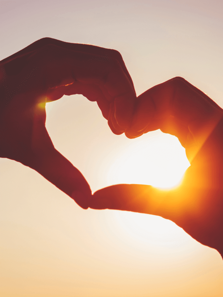 doigts en coeur face à un coucher de soleil pour un voyage surprise